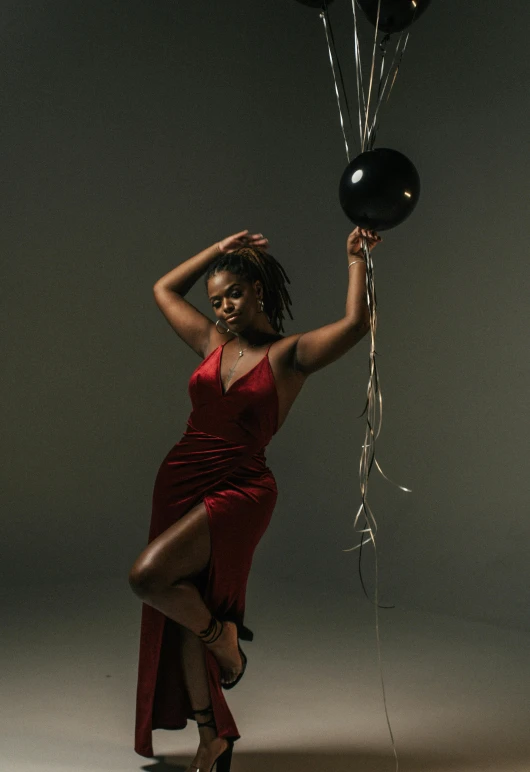 a woman in a red dress holding a bunch of balloons