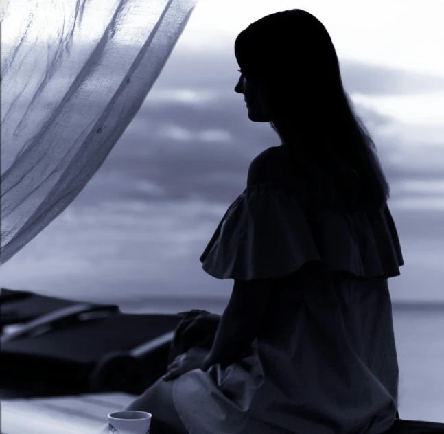 a woman sitting on the ground with a cup