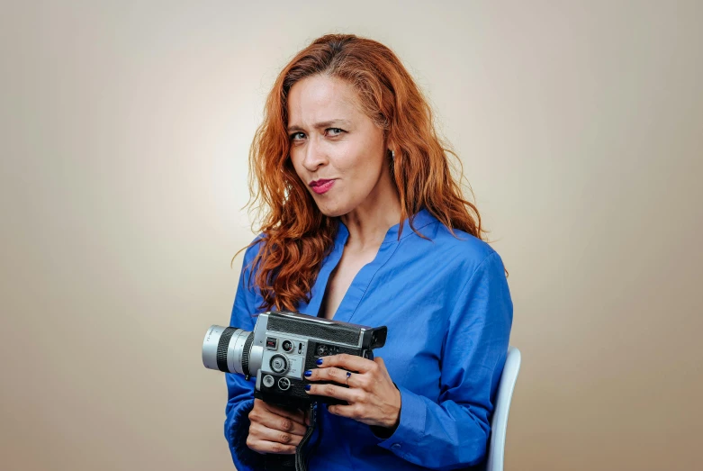 woman holding a camera in her hand and sitting on a chair