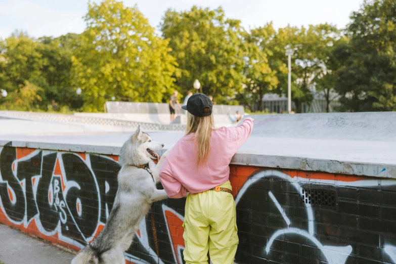 a boy and a girl playing at a skate park with a husky