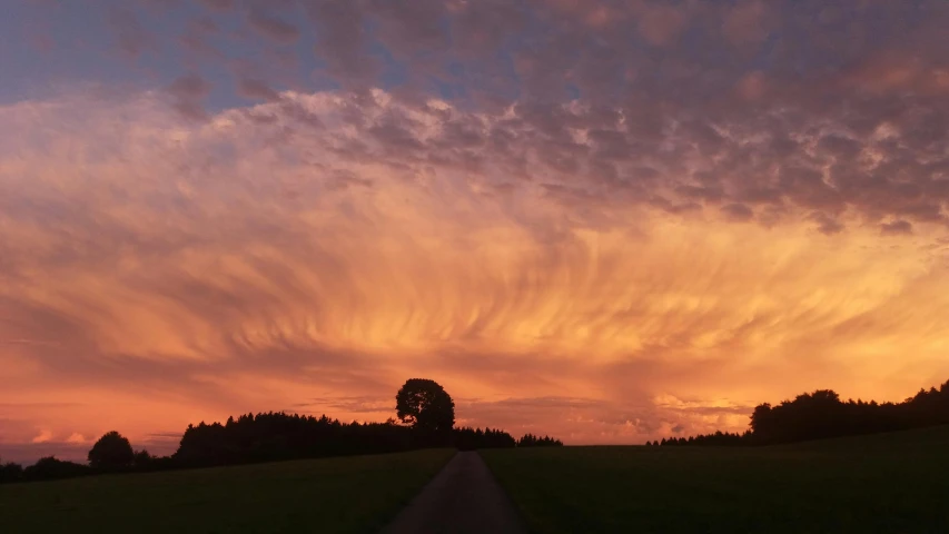 a road with clouds flying above the top