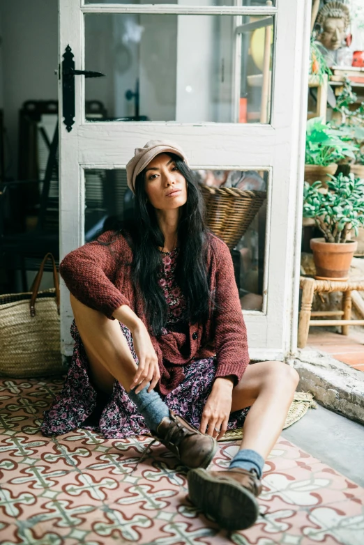 a woman is sitting on the floor next to a pile of shoes