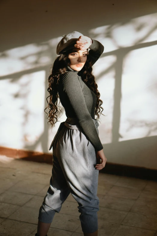 a young woman standing with her arms across her head