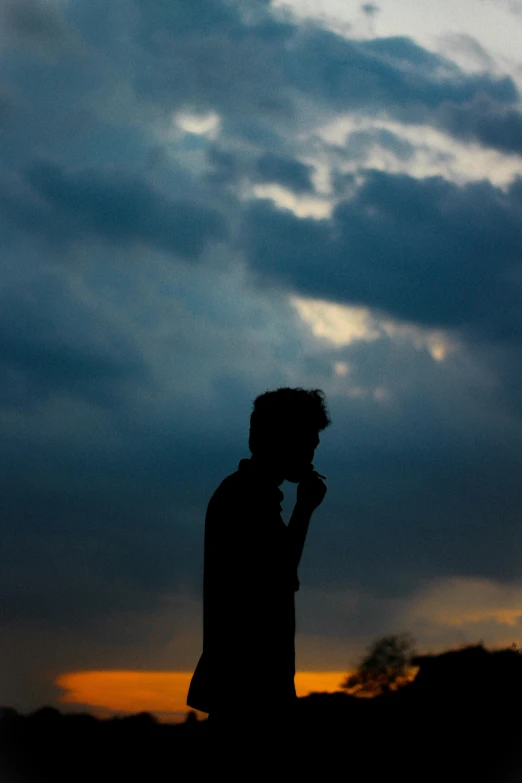 a silhouetted person in the sky talking on a phone