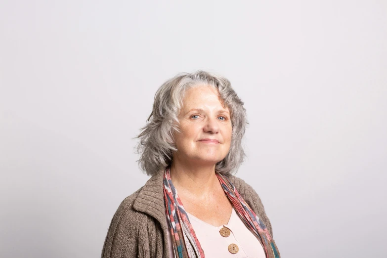 a women standing in front of a white wall with grey hair