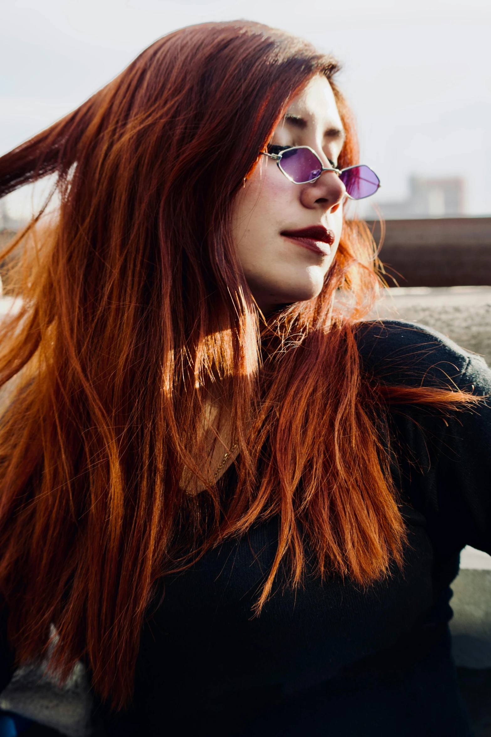 a beautiful young woman with long red hair wearing sunglasses