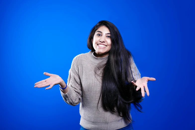 a woman in a gray shirt and a blue background posing for the camera