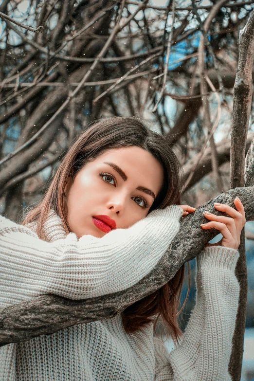 a woman wearing white sweater leaning on tree nch