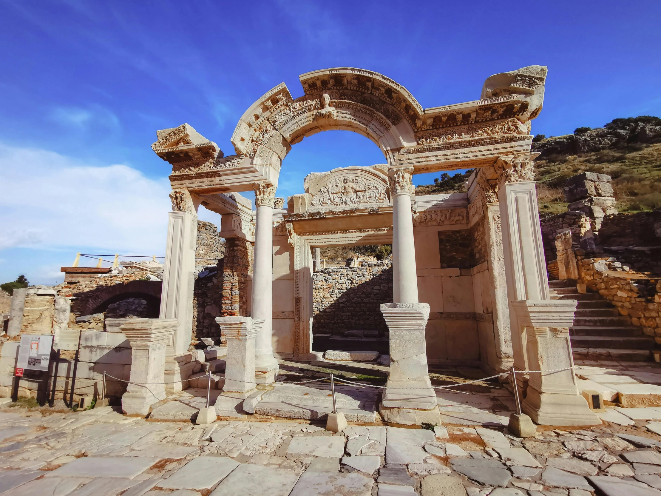 several white pillars against a blue sky with an arch