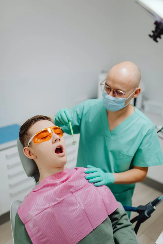 a  getting his teeth brushed by a dentist