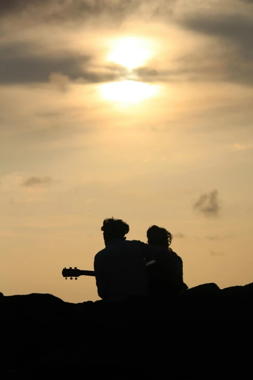 two people looking at the sun with their guitar