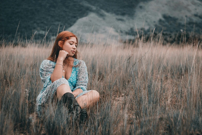 the girl sits on a field talking on her cell phone