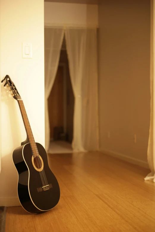 an acoustic guitar sitting on top of a hard wood floor