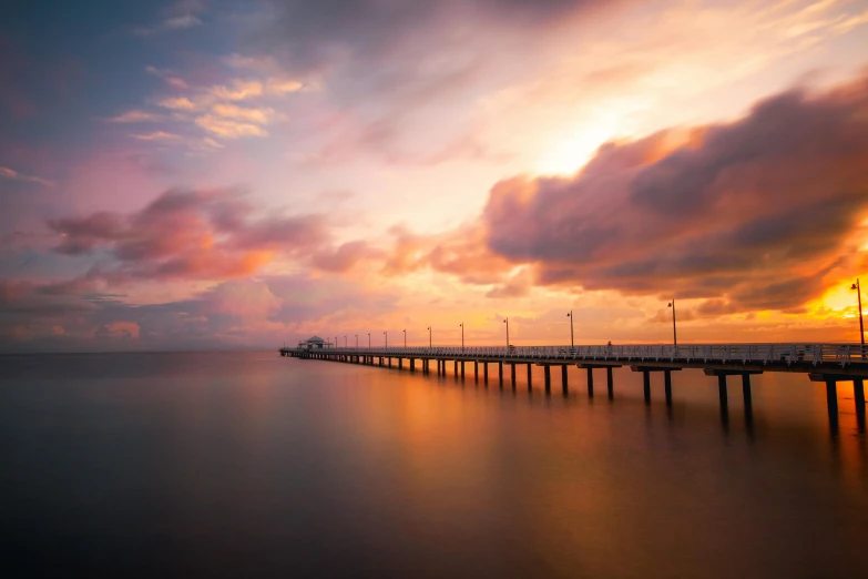 colorful sky and clouds above pier on a bay during sunset