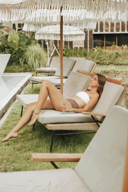 a beautiful woman in white laying on a chaise lounge
