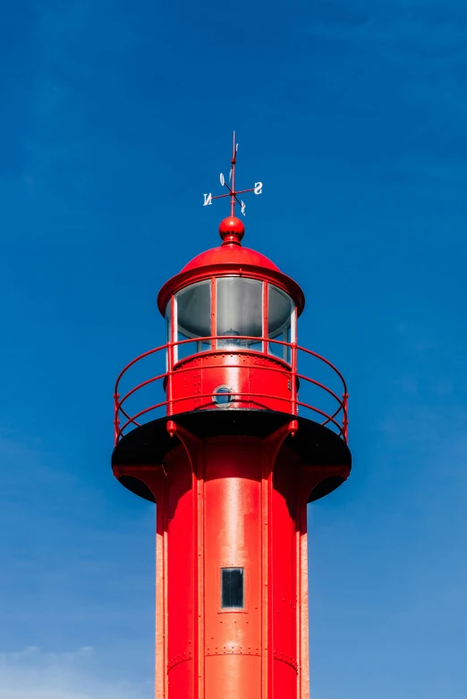 a red lighthouse with a weather vein on top