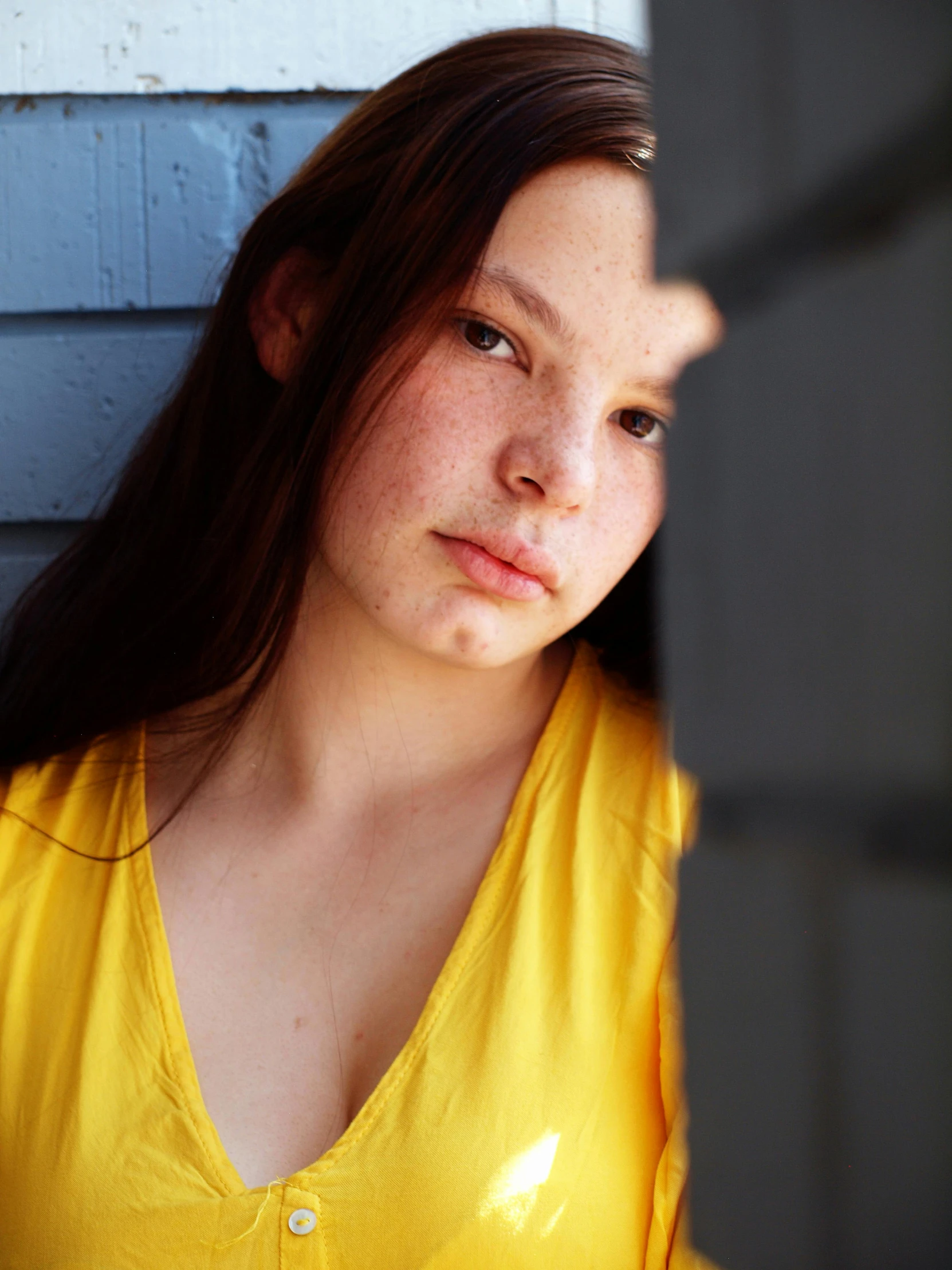 woman in a yellow top looking at soing by a wall