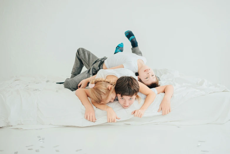 three people laying down in a bed together