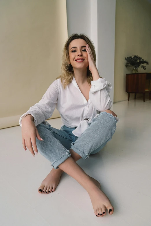 a woman in white top sitting on the ground with her legs crossed