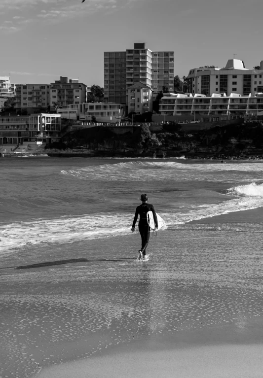 a black and white po of a man on the beach with a surf board