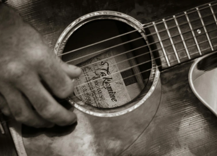 a hand holding an acoustic guitar with strings