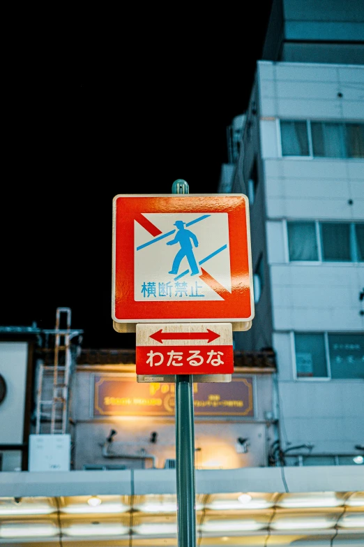 a street sign on a pole with a lit up building in the background