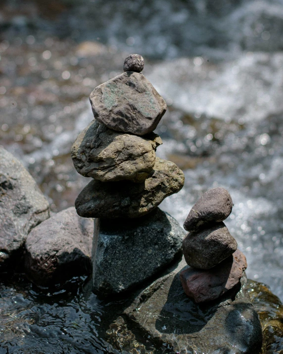 four stones stacked up and resting on top of each other in a pool of water