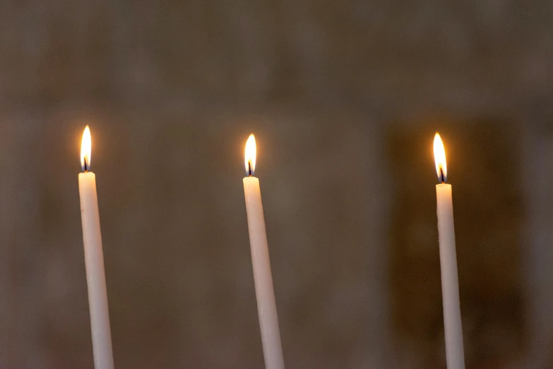 a group of four white candles in front of a dark background