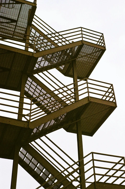 a spiral stair made of metal steps against a gray sky