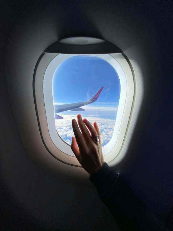 a person holding their hand out the window of an airplane