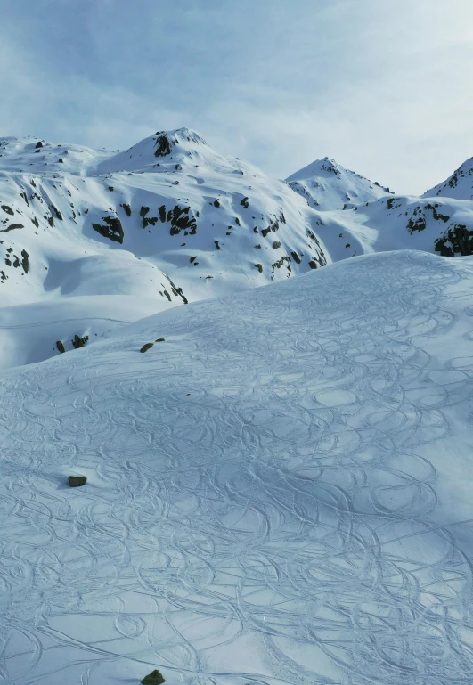 a large snowy slope with some snow covered mountains