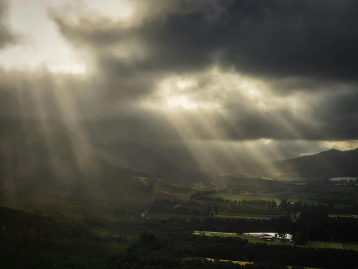 the sun shining through clouds over a valley