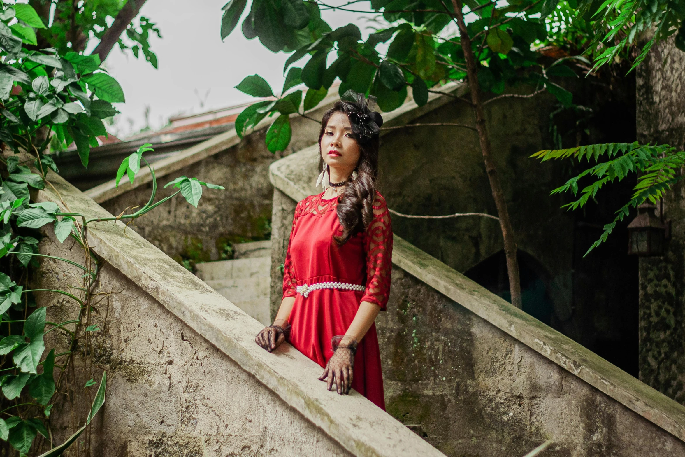 a woman wearing a long red dress looking back over some steps