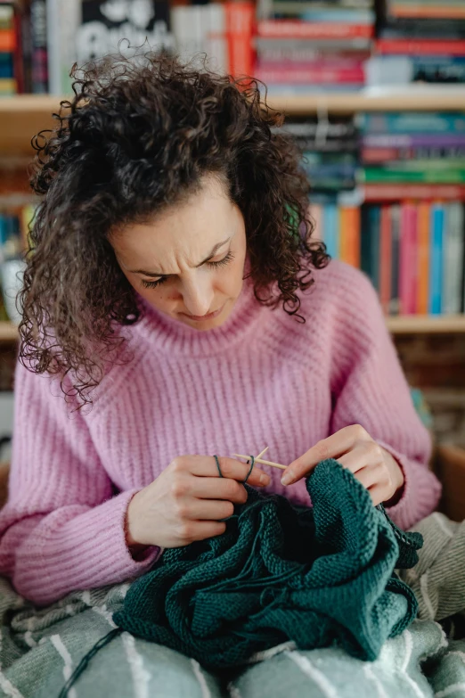 woman working on crochet while sitting in bed