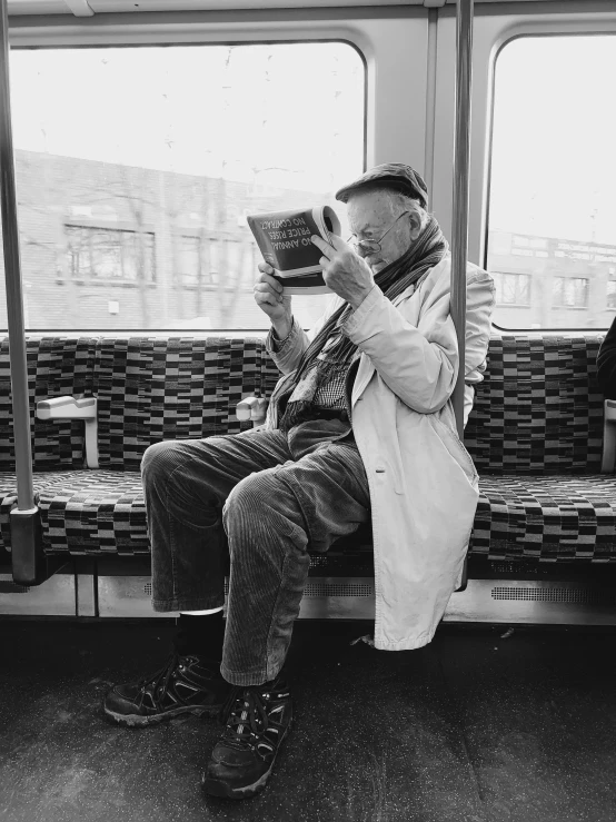 an older man sits on a subway while reading