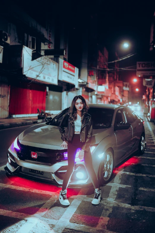 a woman wearing black stands beside her car at night