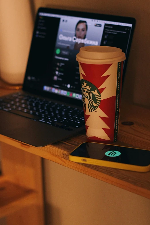 a laptop computer sitting on top of a desk next to a cup