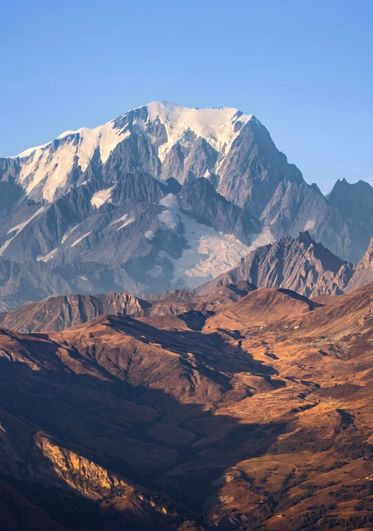 a snowy mountainside with snow covered peaks and a blue sky