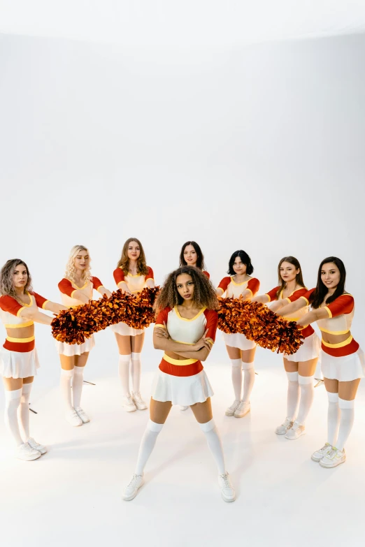 eight cheerleaders standing in the white room wearing cheer outfits