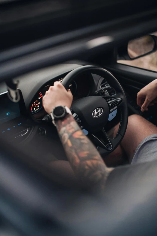 a man with tattoos sits in a car