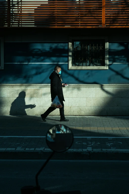 man in mask walking down street by building