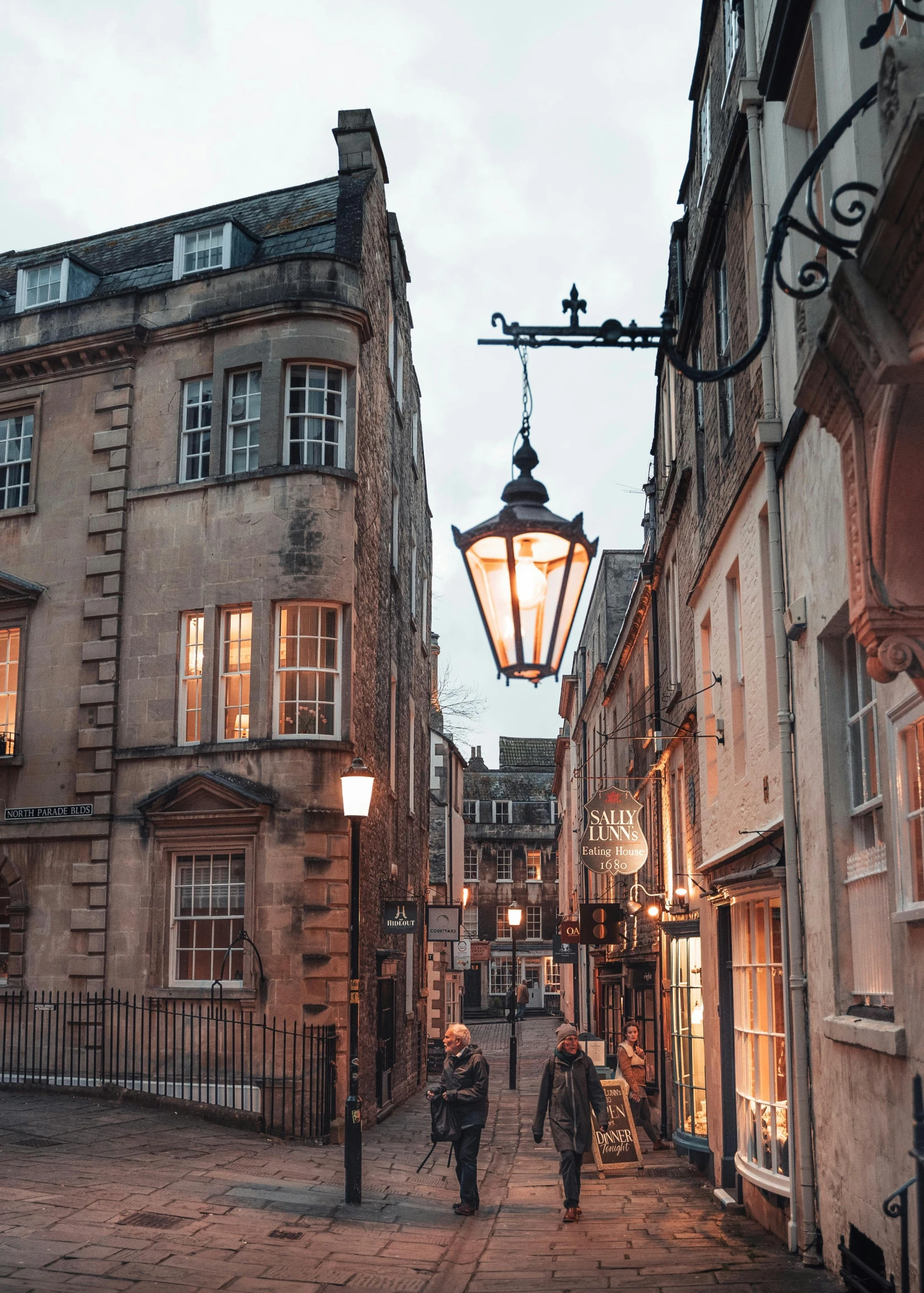 people walking down a sidewalk under a street light