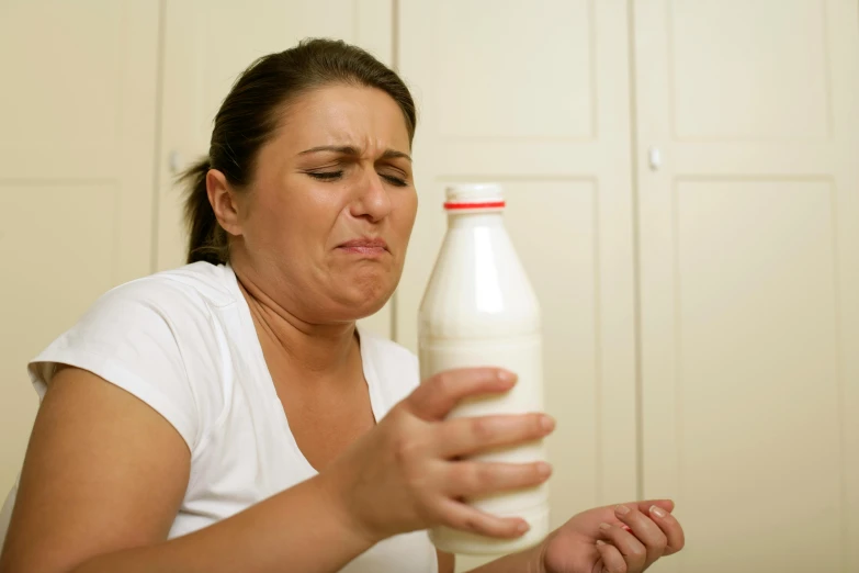 a woman holding a bottle of milk in her hand