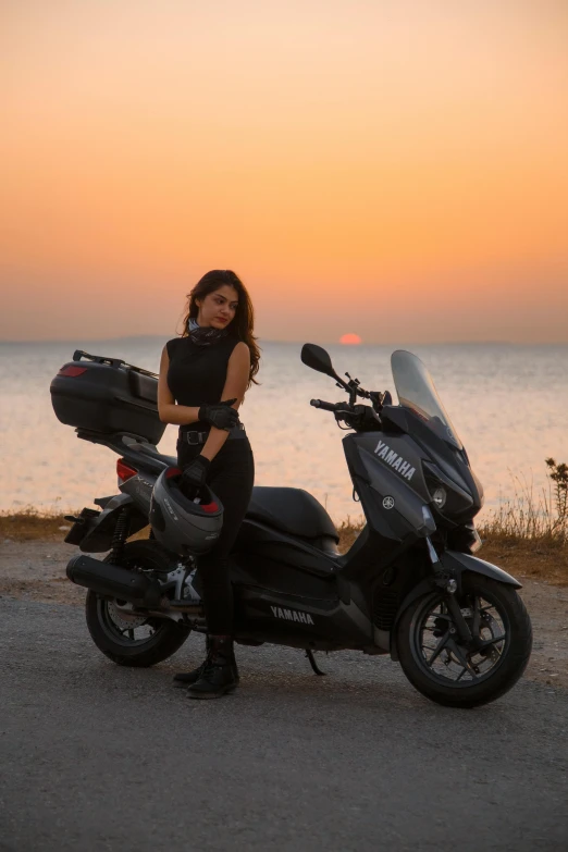 a person standing next to a parked motorcycle at sunset