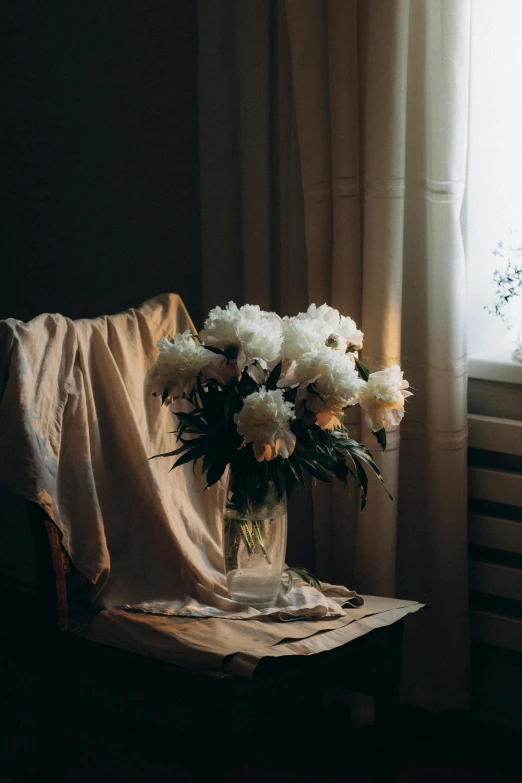 a vase with flowers is on the table by a window