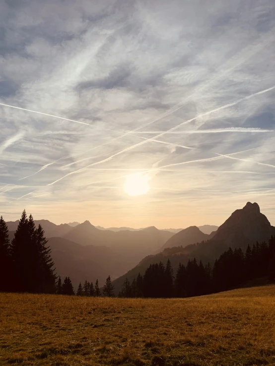 the sun shines brightly over a mountainside as a person in a mountaintop looks on