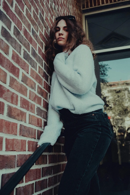 an attractive woman leans against a wall with a cane