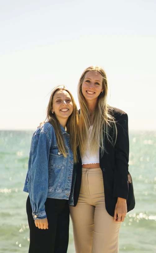 two girls posing in front of the ocean