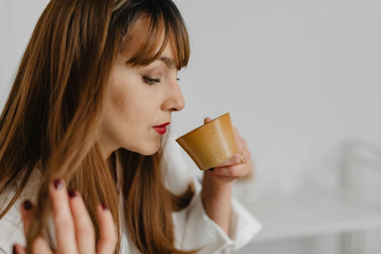 a woman is drinking from a cup while sitting on a couch