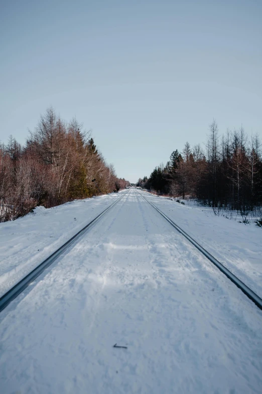 a long stretch of railroad in the snow with tracks in it